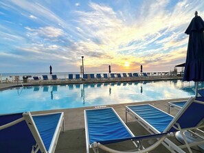 A swimming pool with lounge chairs and a sunset view. - Beachfront! Heated pool, spa, Tiki bar & Views! (Panama City Beach)