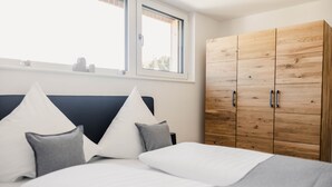 Une chambre à coucher avec un lit, des oreillers, une armoire et une fenêtre.