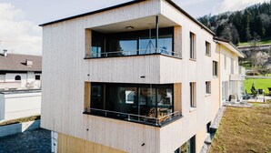 Un bâtiment moderne à deux étages, doté d’une façade en bois, de grandes fenêtres et d’un balcon.