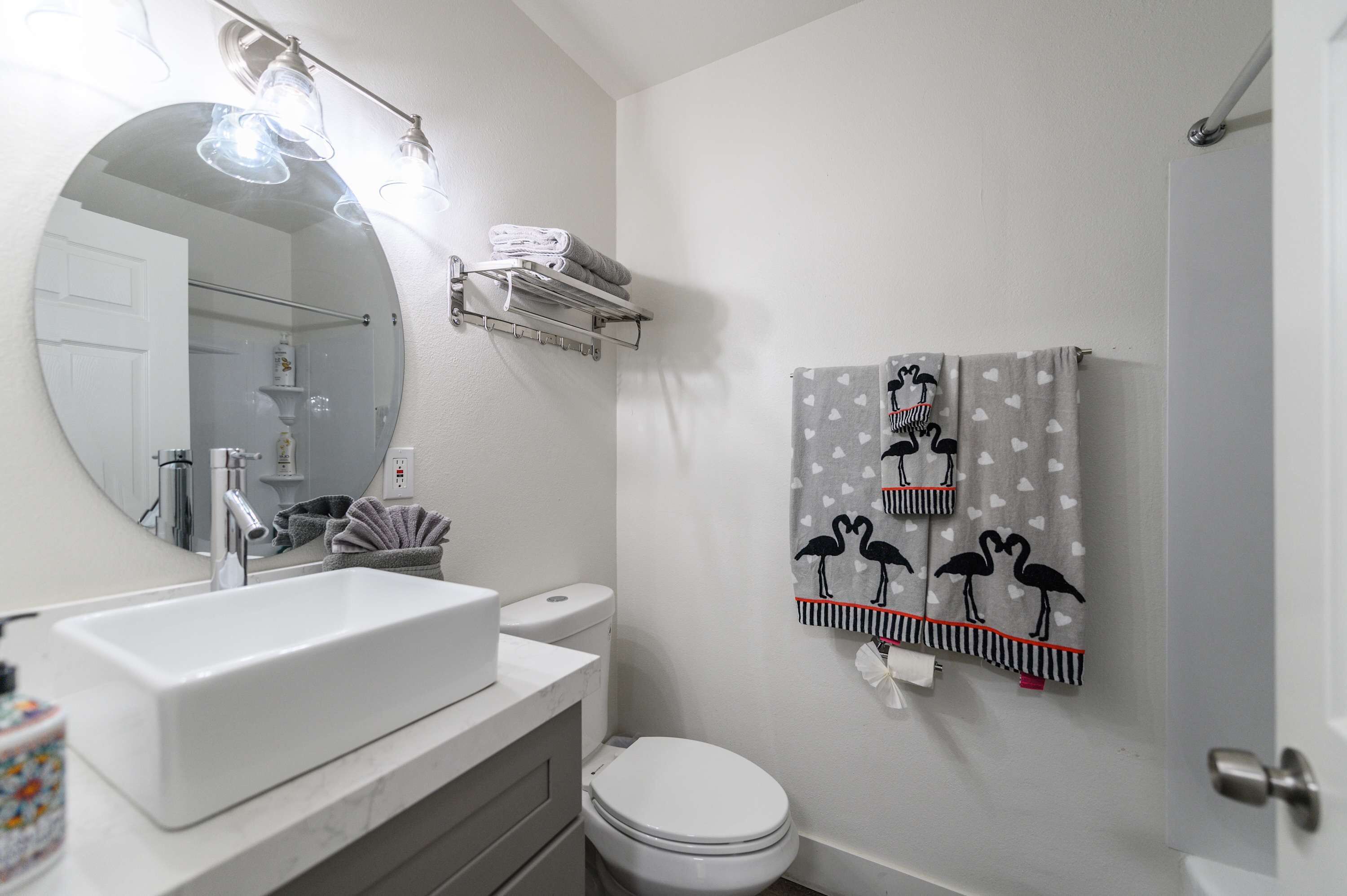 A bathroom with a white sink, toilet, and a towel rack with patterned towels.