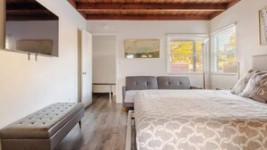 A bedroom with a bed, bench, and a view of the outside. - Disneyland/Knott's, 5BR 4BA, No Tax, Large Parking (Fullerton)