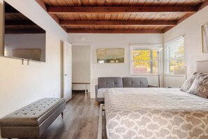 Un dormitorio con cama, banca y vistas al exterior.