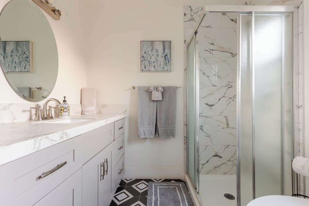 Une salle de bain avec un lavabo en marbre, une cabine de douche en verre et un carrelage décoratif.
