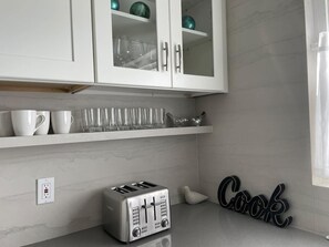 A kitchen with white cabinets, a toaster, and a 'Cook' sign.