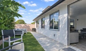 Una casa moderna con un patio, mobiliario exterior y un ventanal grande.