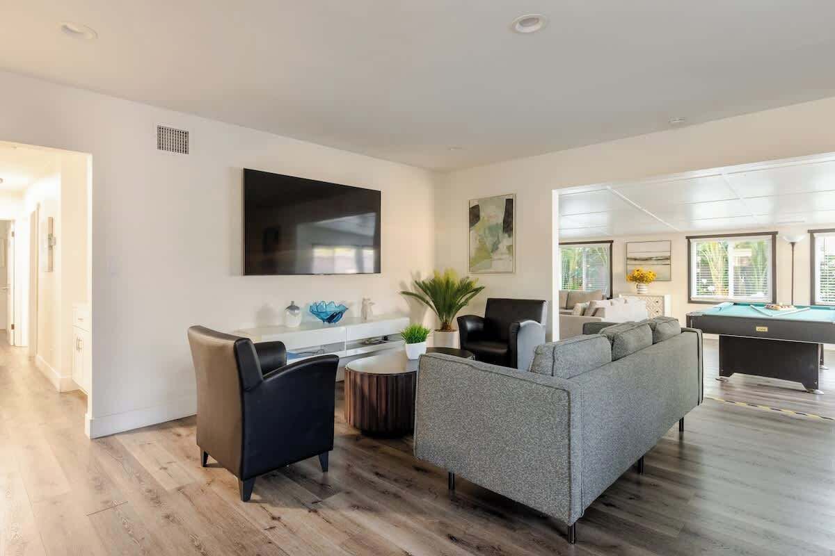 Una sala de estar moderna con sofá, sillón y mesa de billar.