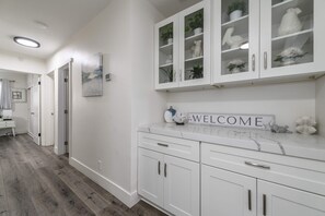 A hallway with white cabinetry, a welcome sign, and a plant on the counter. - Disneyland/Knott's, 5BR 4BA, No Tax, Large Parking (Fullerton)