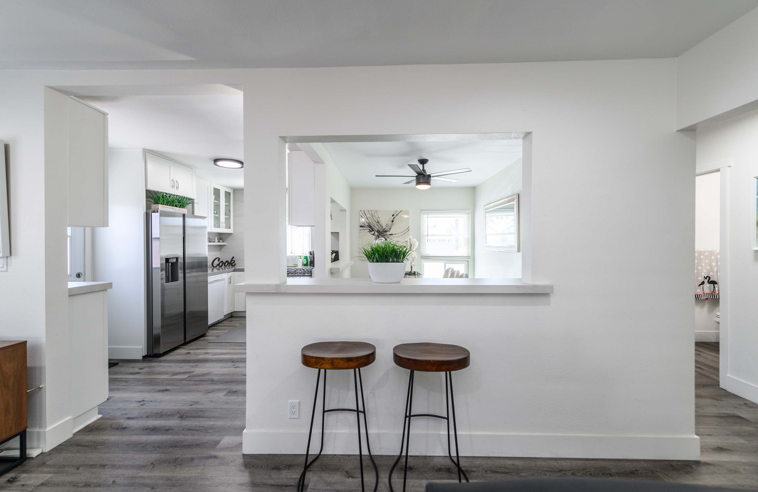 A modern kitchen with white cabinetry, a stainless steel refrigerator, and a central island with stools.
