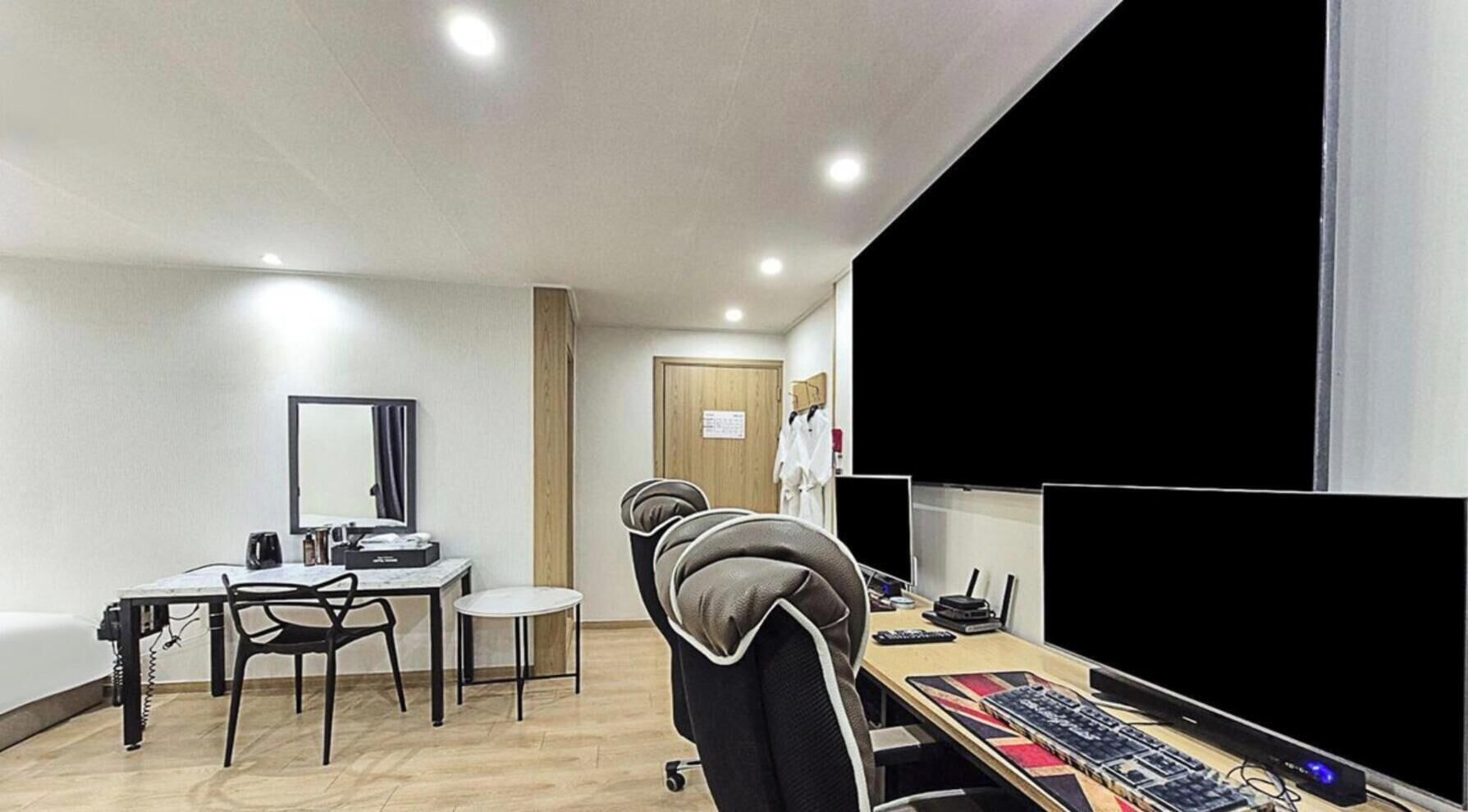 A modern room with a desk, chair, and a large screen.