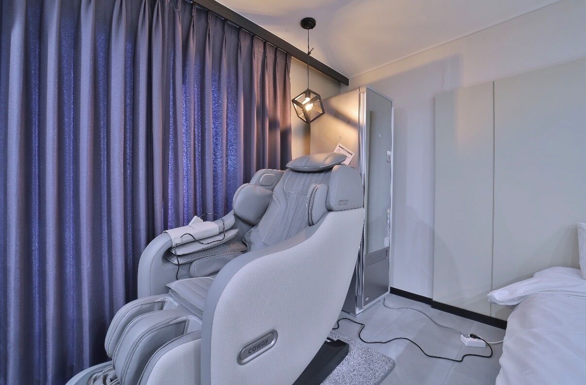 Una habitación de hotel moderna con sillón de masajes, televisor de pantalla plana y cama.