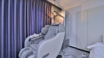 Una habitación de hotel moderna con sillón de masajes, televisor de pantalla plana y cama.