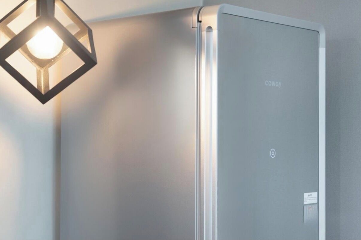 A modern, minimalist room with a built-in air conditioning unit labeled 'COWAY' and a geometric pendant light fixture.