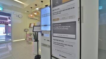 A hotel reception area with a digital display, a clock, and a VENDIT sign.