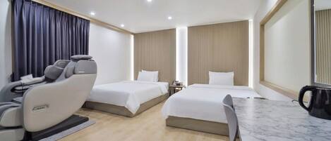 A hotel room with two beds, a massage chair, a table, and a coffee maker.