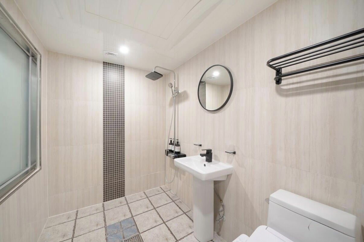 A bathroom with a shower, sink, toilet, and a mirror.