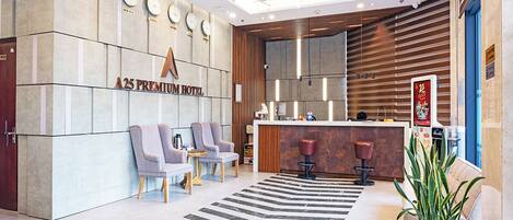 A modern hotel lobby with a reception desk, seating area, and a large plant.