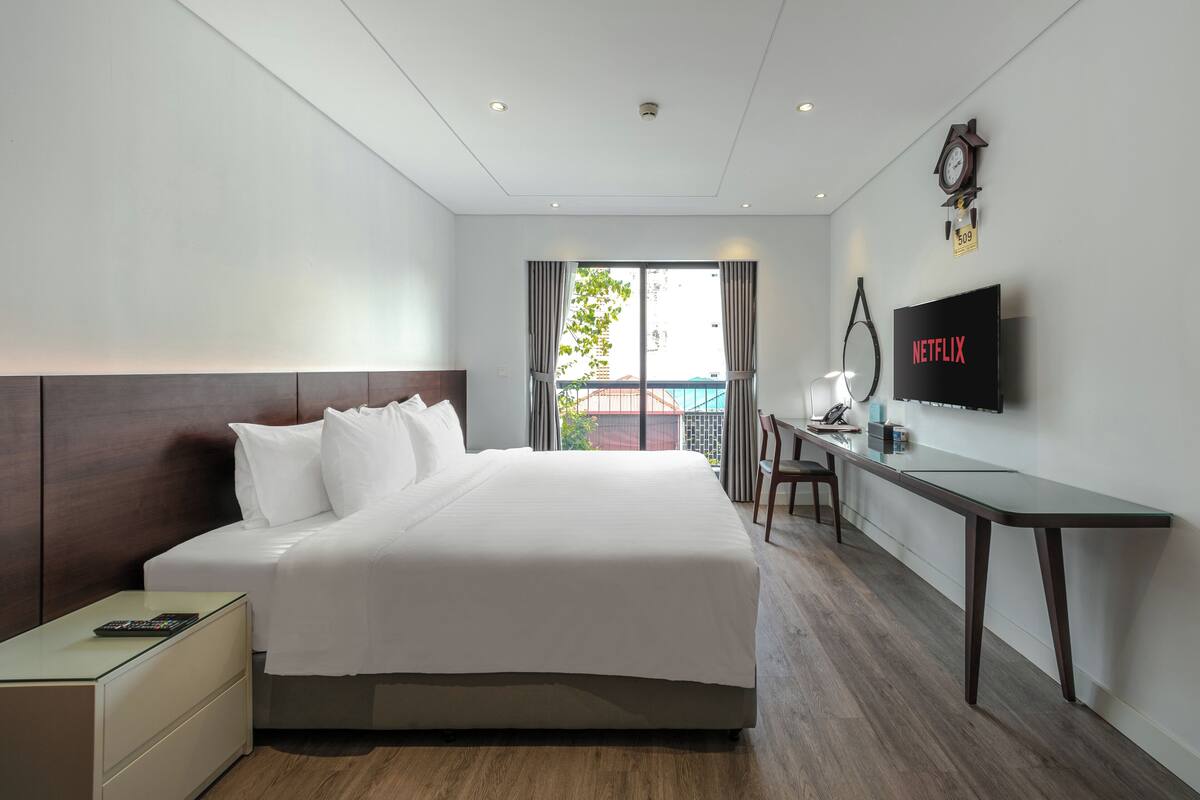 A hotel room with a bed, desk, and TV.