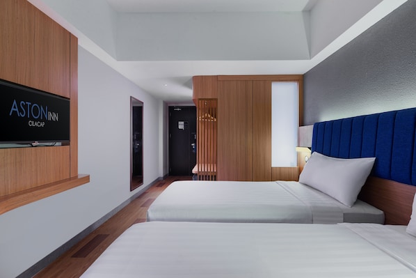 A hotel room with two beds, a TV mounted on the wall, and a wooden panel design.