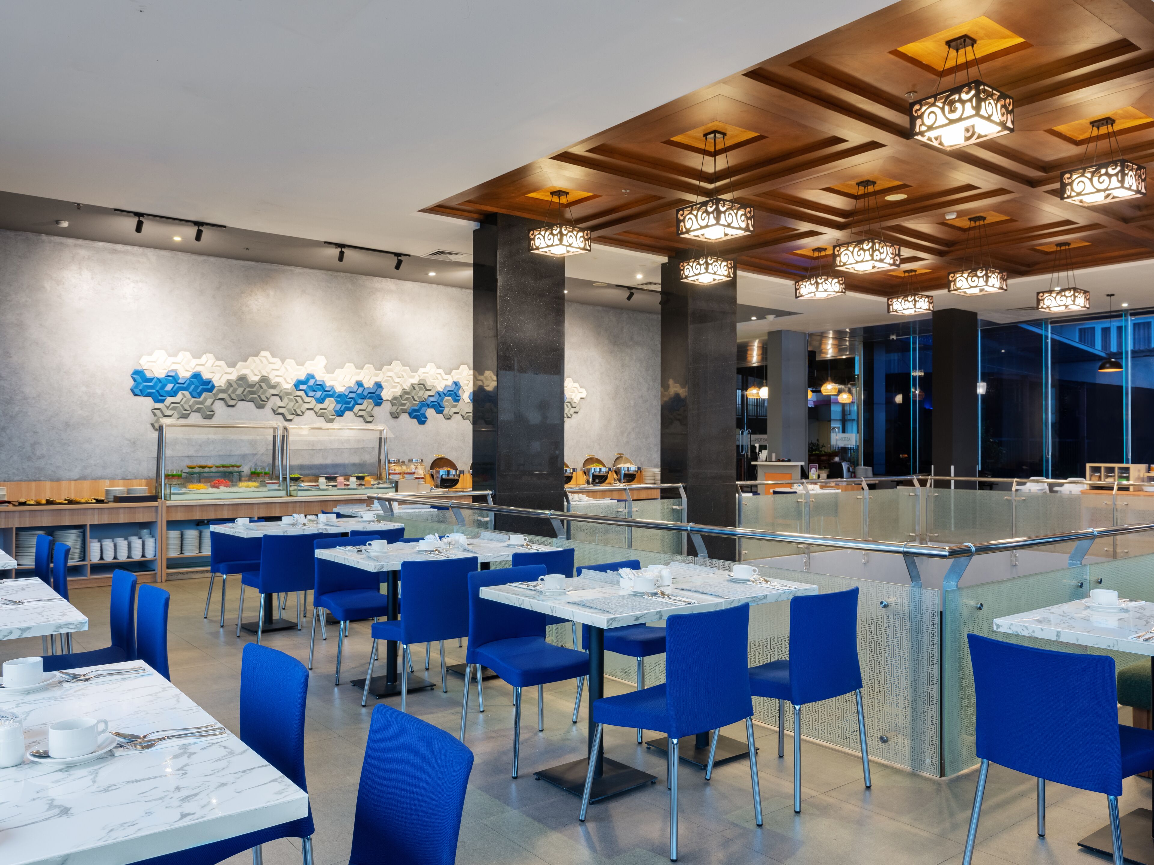Un comedor moderno con mesas de mármol, sillas azules y arte decorativo en la pared.