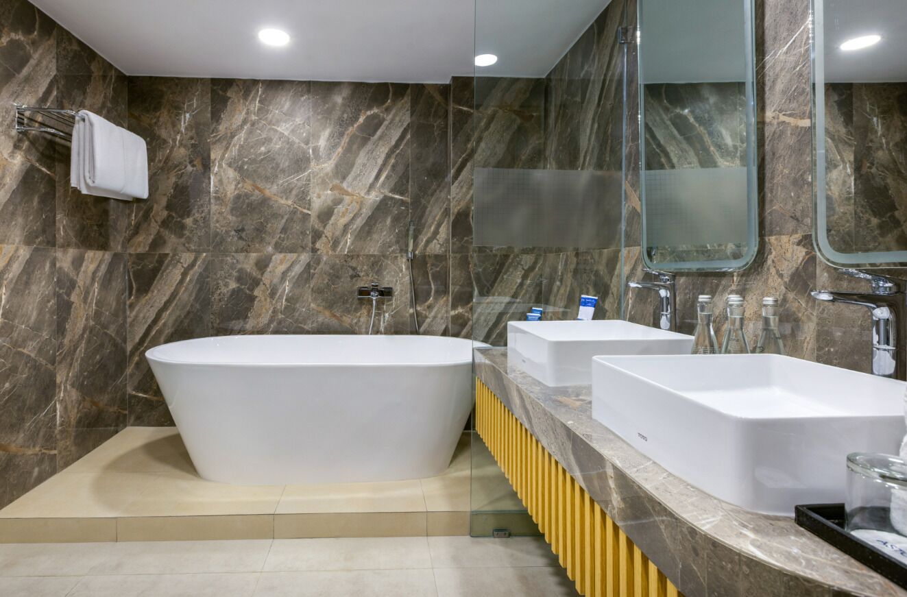 Un bagno moderno con una vasca freestanding, due lavandini e un grande specchio.