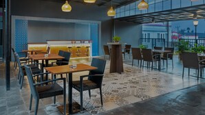 Un restaurante moderno con techos altos, lámparas de mimbre colgantes y un suelo estampado.