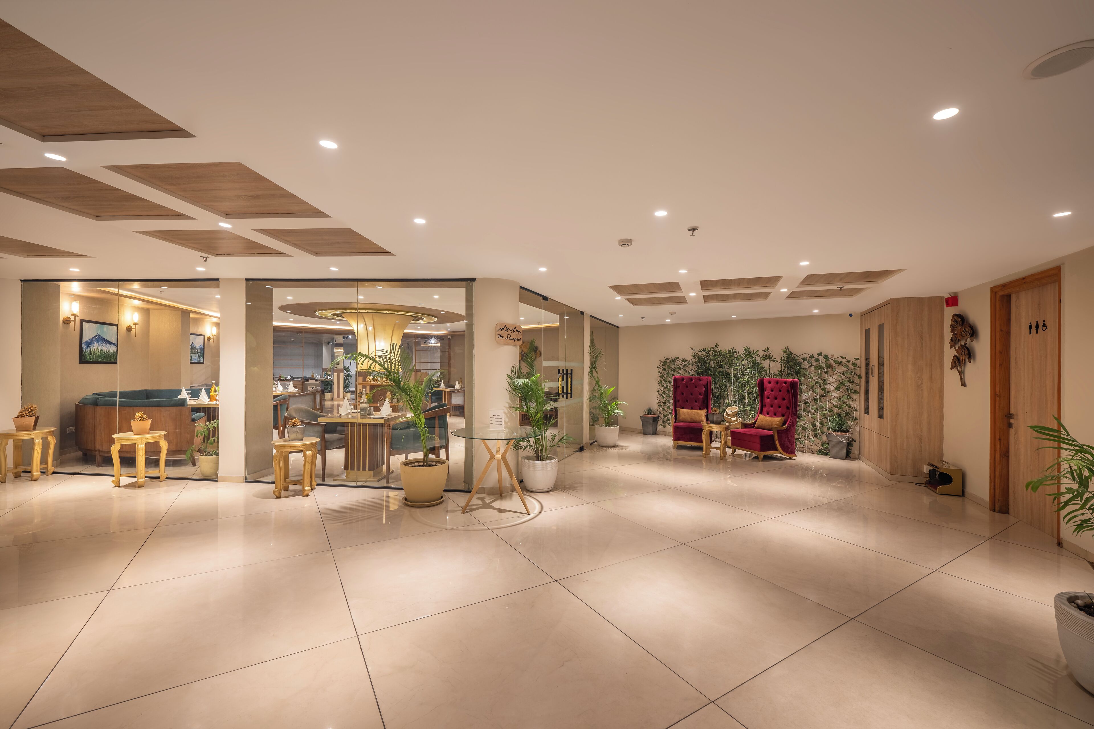 A spacious lobby with a reception desk, seating area, and a large plant.