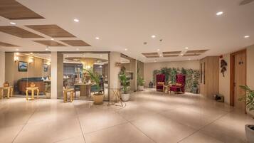 A spacious lobby with a reception desk, seating area, and a large plant.