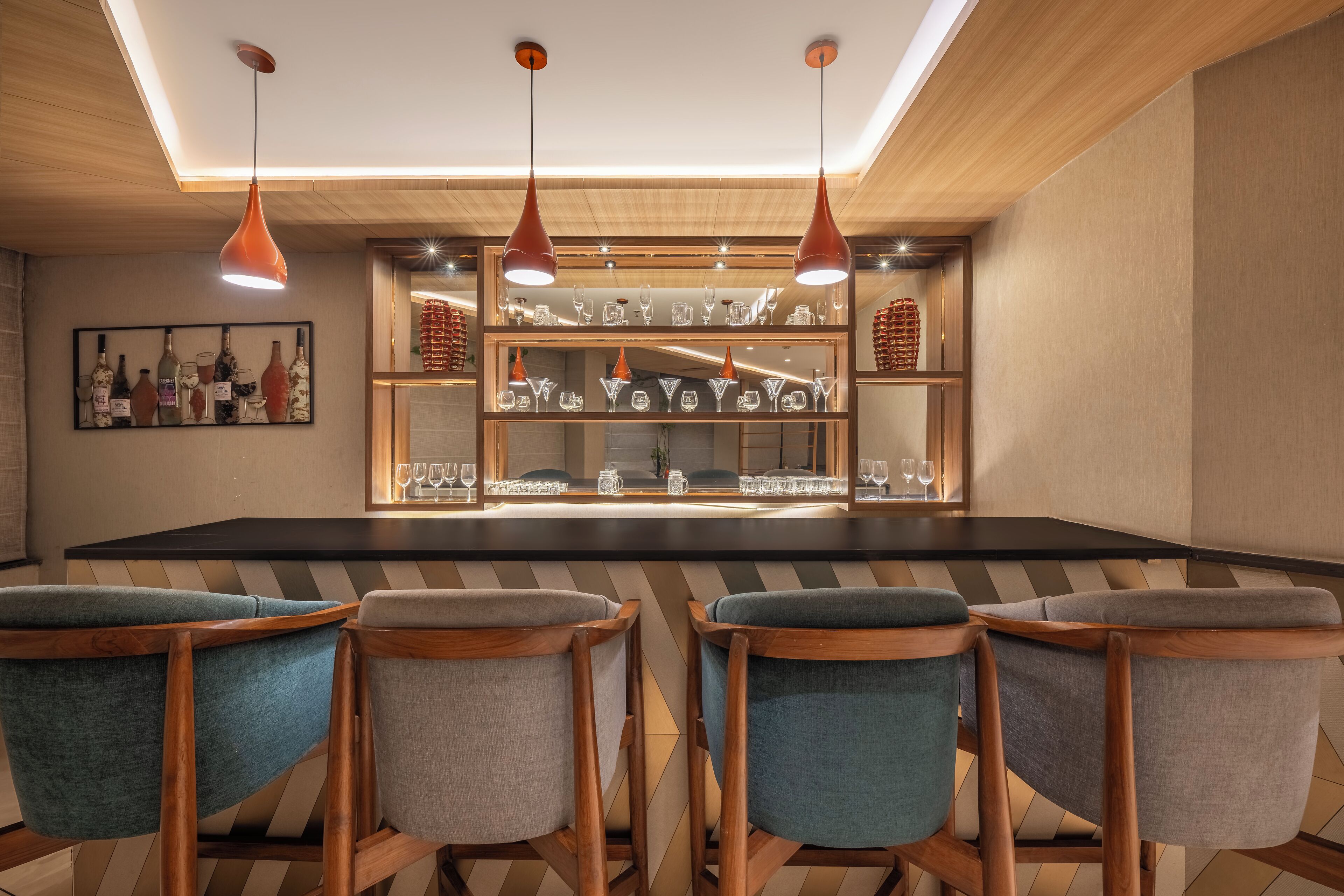 A bar area with wooden chairs, pendant lights, and shelves of glassware.
