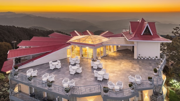 Un hotel con terraza, mobiliario exterior y vistas del paisaje circundante.
