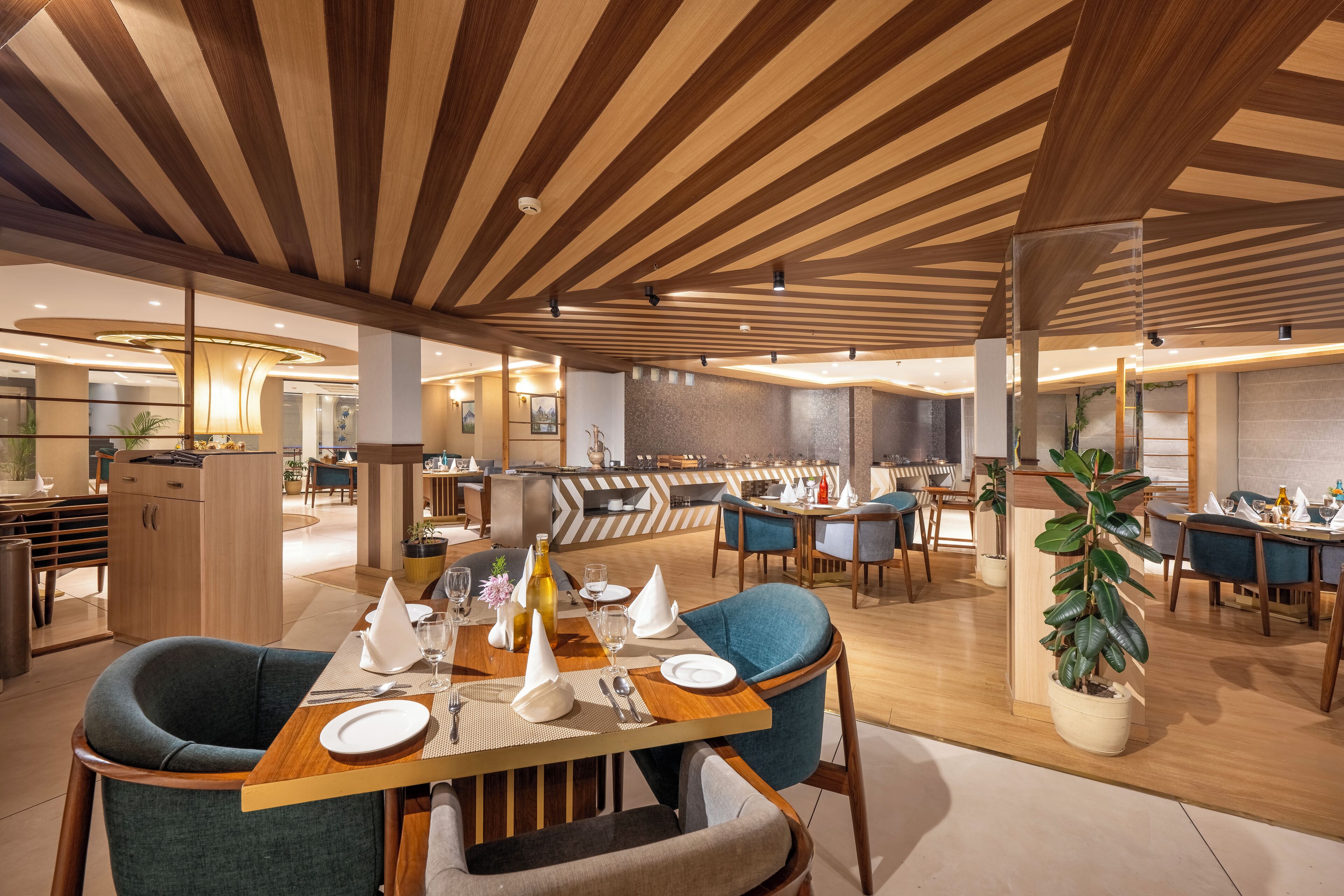A modern dining area with wooden ceiling beams, a central table set for a meal, and a potted plant.