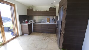 Eine moderne Küche mit dunklen Holzschränken, einem Edelstahlspülbecken und einem großen Fenster mit Blick auf einen Garten.