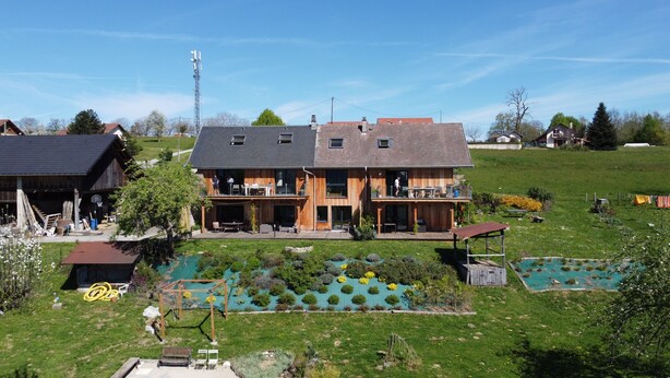Ein zweistöckiges Holzhaus mit Balkon, Schwimmbad und Garten.