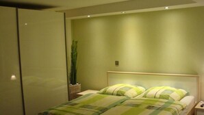 A bedroom with a bed, a nightstand, a lamp, and a potted plant. - Directly on the water with its own jetty in Berlin - Köpenick (Berlin)