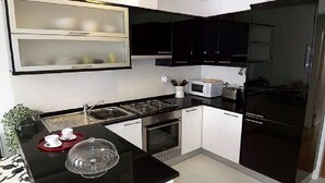 A modern kitchen with black cabinets, a microwave, a toaster, and a sink. - Graça Terrace (Lisboa)