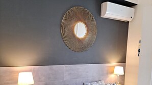 A bedroom with a bed, two bedside tables, a wall-mounted air conditioner, and a decorative mirror. - Graça Terrace (Lisboa)