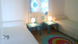 A room with two beds, a window with circular patterns, and a colorful rug. - 4-star waterfront villa with exceptional sea views (Sari Solenzara)