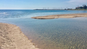 A beach with clear shallow waters and a distant pier. - 4-star waterfront villa with exceptional sea views (Sari Solenzara)