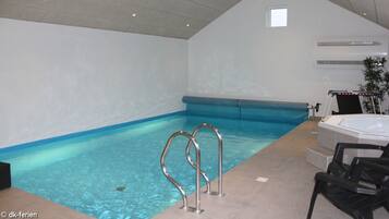 Relax by the rectangular pool, featuring a hot tub and metal ladders for easy access.