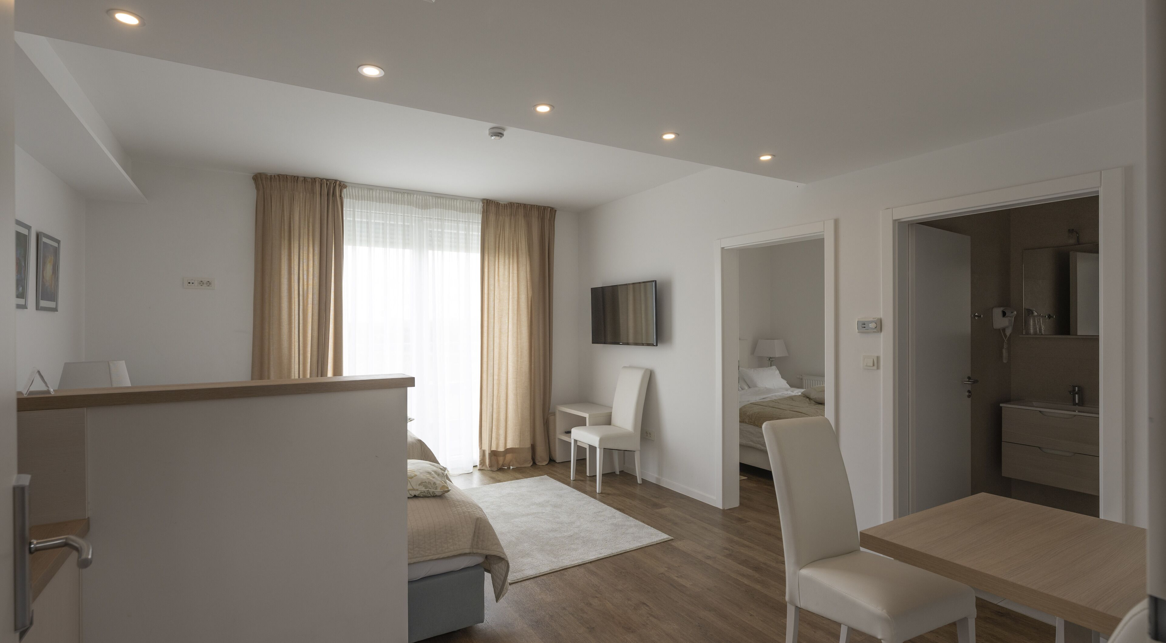 Una habitación de hotel moderna con cama, escritorio, silla, televisor y baño.