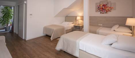 Een hotelkamer met twee bedden, een bloempot, een plafondlamp en een schilderij aan de muur.