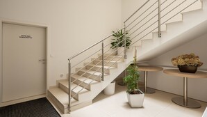 A modern hotel lobby with a staircase, a reception desk, and a potted plant. - Hotel Magdalena (Zagreb)