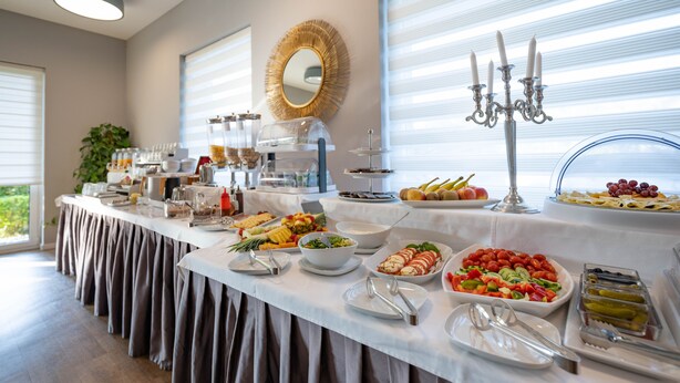 A buffet table with various food items and utensils, a mirror on the wall, and a candelabra. - Hotel Magdalena (Zagreb)