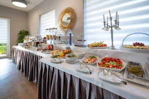 Una mesa de buffet con diversos alimentos y utensilios, un espejo en la pared y un candelabro.