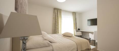 Une chambre à coucher moderne avec un lit, une table de chevet, une lampe et un bureau avec une chaise.