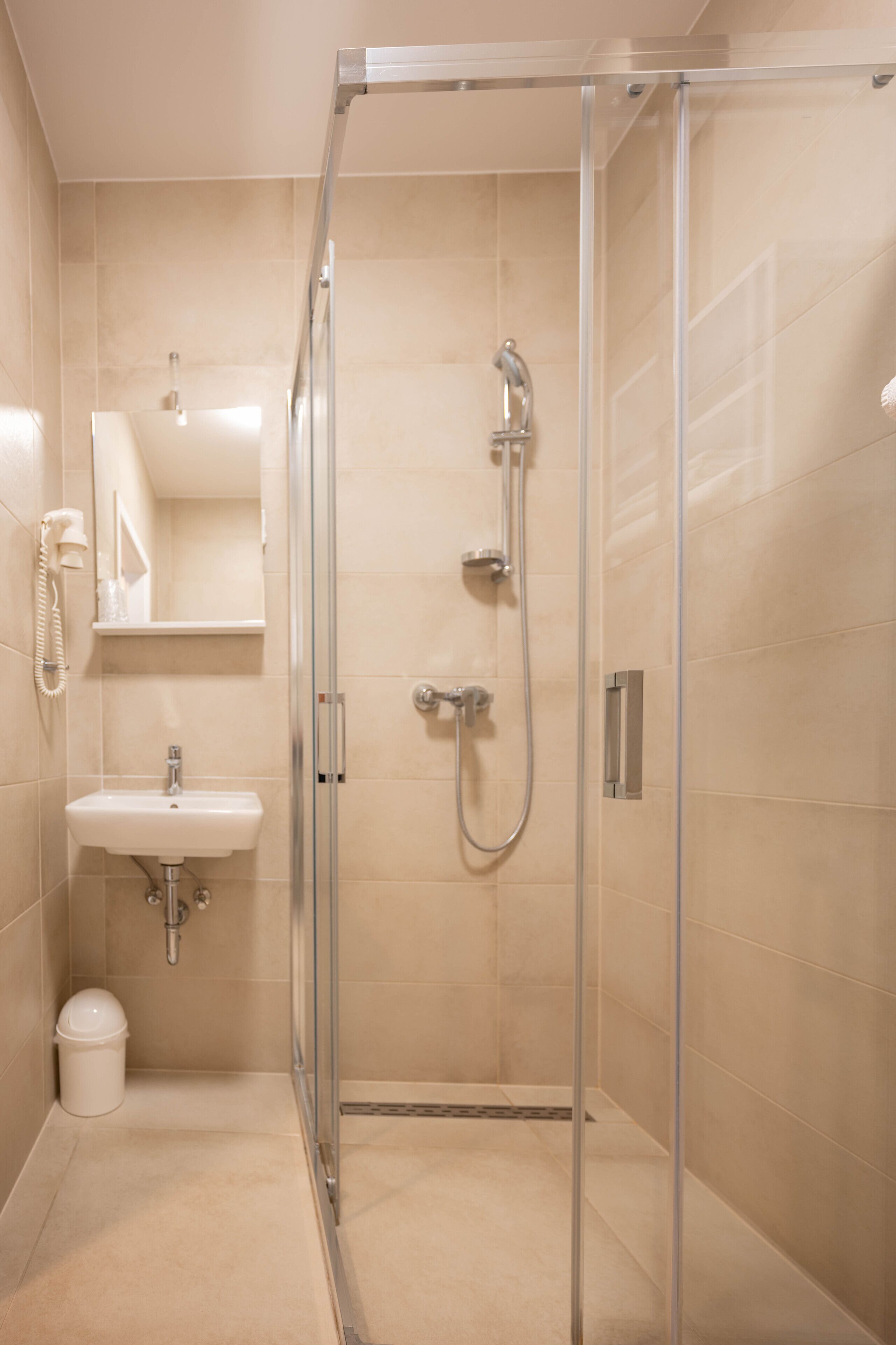 A modern bathroom with a glass-enclosed shower, a sink, and a mirror.