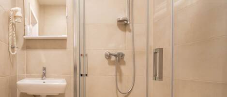 A modern bathroom with a glass-enclosed shower, a sink, and a mirror.