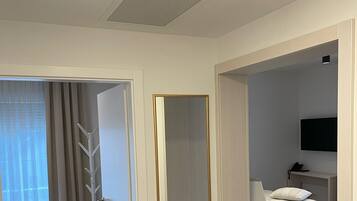 Moderni hotellihuone, jossa on sänky, yöpöytä ja televisio.