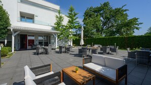 A modern outdoor patio with wicker furniture, a wooden table, and a white sofa. - Hotel Magdalena (Zagreb)