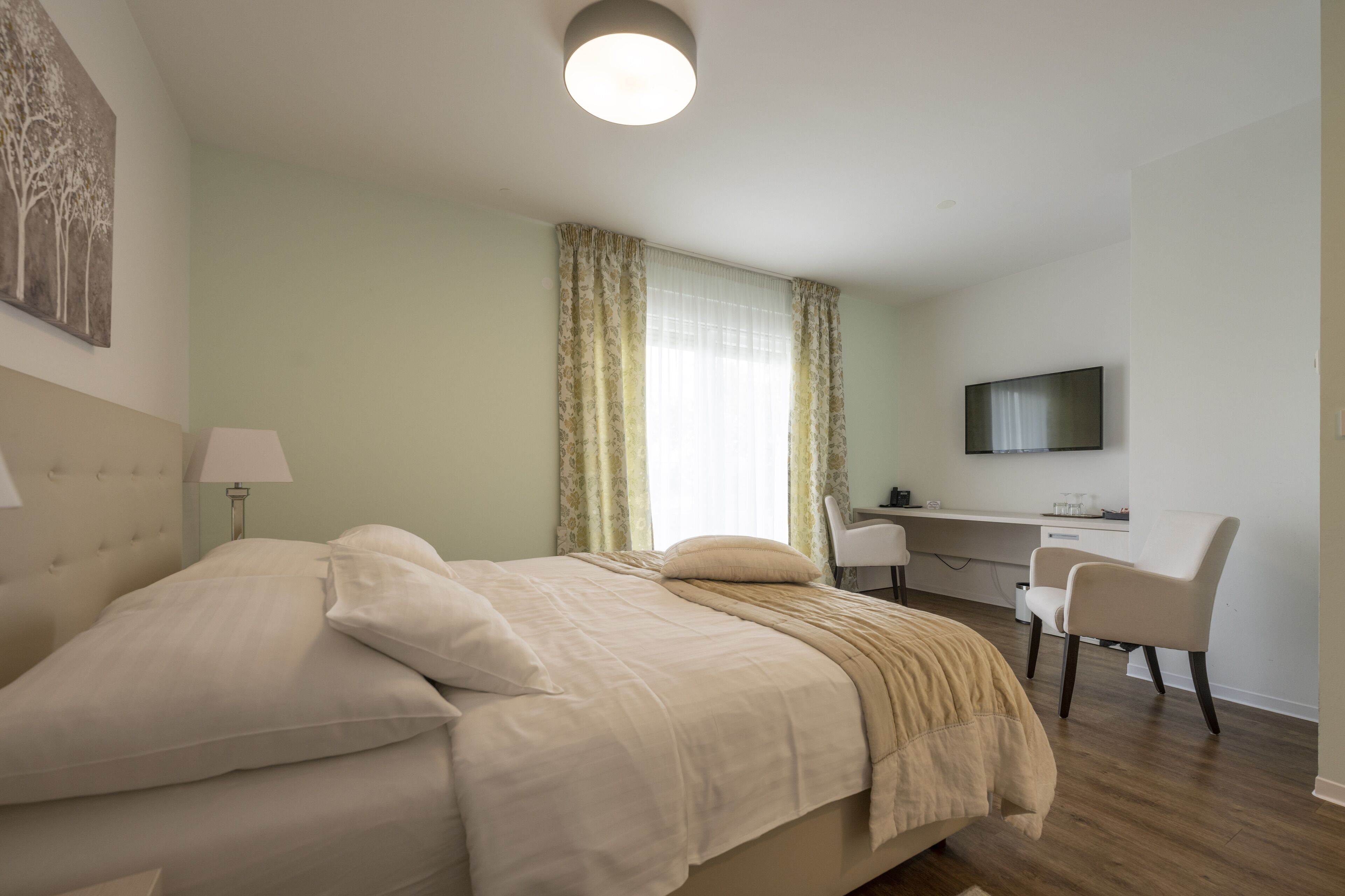 A bedroom with a bed, a desk, a chair, and a television.