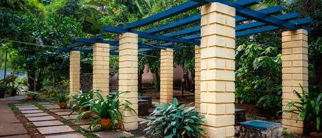 A garden with a pergola structure, potted plants, and a stone pathway.